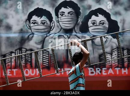 Guwahati, Assam, Inde. 1 mai 2020. Un travail porte une échelle marchant devant une murale liée au coronavirus, pendant le maintien à l'échelle nationale à la suite de la pandémie de coronavirus, à Guwahati. Crédit: David Talukdar/ZUMA Wire/Alay Live News Banque D'Images