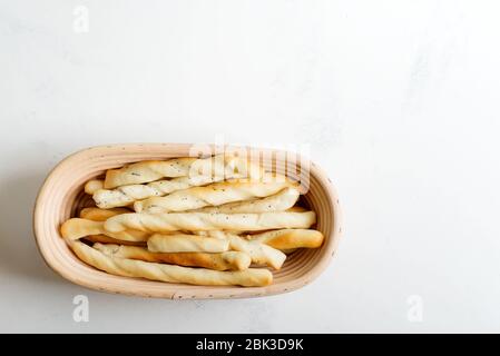 Bâtonnets de pain maison traditionnels italiens fraîchement cuits, graissini aux graines de pavot dans un panier sur fond de marbre gris clair, espace copie. Nouveau ita Banque D'Images