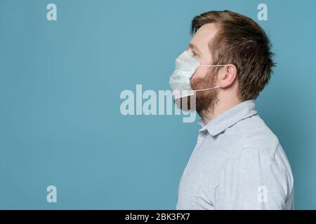 Homme avec une barbe chatourée à cause de laquelle le masque médical ne s'adapte pas parfaitement et ne crée pas une protection complète. Espace de copie. Banque D'Images