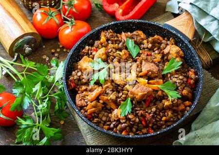 Cuisine indienne. Lentilles vertes épicées indiennes traditionnelles avec viande, épices, herbes dans une poêle à frire en fonte sur une table en bois. Banque D'Images