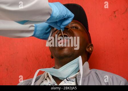 Un agent de santé effectue un test de bouche-à-oreille sur un résident pendant la pandémie du virus corona. Un test de masse des cas COVID-19 dans la région de Kawangware a été effectué sur les résidents. Jusqu'à présent, le Kenya a signalé 411 cas de coronavirus, 144 reprises et 17 décès. Banque D'Images