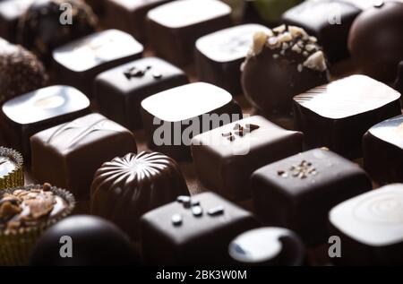 Truffes au chocolat noir et au lait de luxe. Assortiment de délicieux pralines au chocolat faites à la main à la suite. Arrière-plan plein format. Prise de vue en studio. Gros plan. Banque D'Images