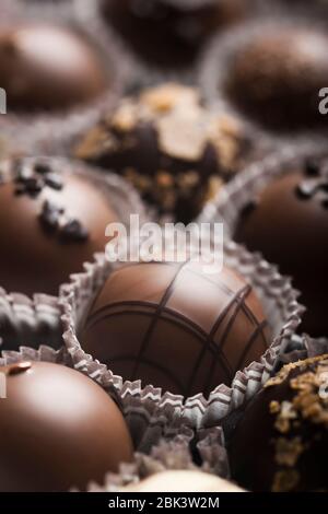 Truffes au chocolat noir et au lait de luxe. Assortiment de délicieux pralines au chocolat faites à la main à la suite. Arrière-plan plein format. Prise de vue en studio. Gros plan. Banque D'Images