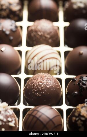 Truffes au chocolat noir et au lait de luxe. Assortiment de délicieux pralines au chocolat faites à la main à la suite. Arrière-plan plein format. Prise de vue en studio. Gros plan. Banque D'Images