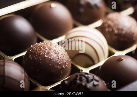 Truffes au chocolat noir et au lait de luxe. Assortiment de délicieux pralines au chocolat faites à la main à la suite. Arrière-plan plein format. Prise de vue en studio. Gros plan. Banque D'Images