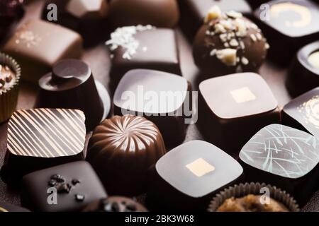 Truffes au chocolat noir et au lait de luxe. Assortiment de délicieux pralines au chocolat faites à la main à la suite. Arrière-plan plein format. Prise de vue en studio. Gros plan. Banque D'Images