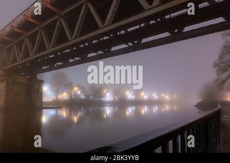 Un pont de chemin de fer d'acier de l'époque victorienne sur une rivière sur un hivers brumeux atmosphérique moody, nuit. Worcester, River 7, UK Banque D'Images