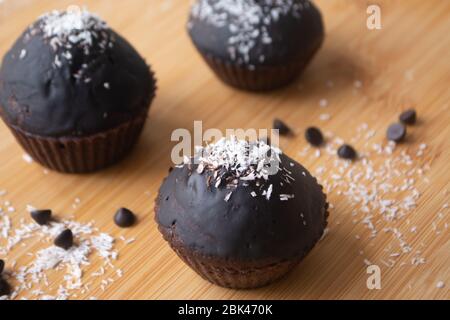 Chocolat glacé chocolat cacao gâteau muffins avec flocons de noix de coco en rangées sur un panier de refroidissement en métal Banque D'Images