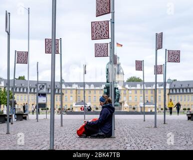 Allemagne. 01 mai 2020. À Karlsruhe, à la Platz für Grundrechte, vous trouverez des panneaux indiquant la loi (œuvres d'art de Jochen Gerz). À l'un des signes se trouve une femme avec une affiche des droits fondamentaux et médite. Le château en arrière-plan. GES/vie quotidienne à Karlsruhe pendant la crise corona, 01.05.2020 GES/vie quotidienne pendant la crise corona à Karlsruhe, Allemagne. 01.05.2020 | utilisation dans le monde crédit: dpa/Alay Live News Banque D'Images