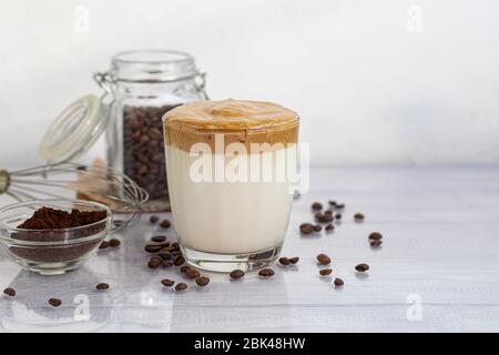 Le café Dalgona est une boisson froide et tendance de la Corée. Café savoureux et aromatique avec lait et sucre dans un verre sur fond blanc. Espace de copie Banque D'Images