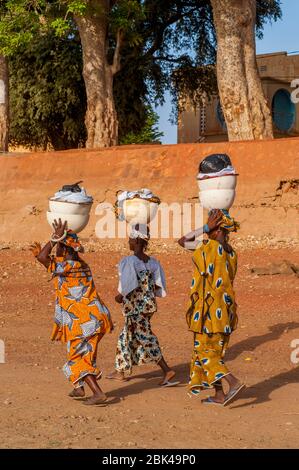 Les femmes de la région marchant et portant la lessive sur leur tête sur le rivage de la rivière Bani à Mopti au Mali, en Afrique de l'Ouest. Banque D'Images