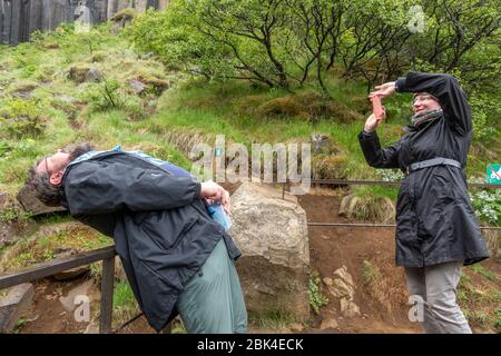 Couple prenant une photo amusante (d'une « cascade »), cascade de Svartifoss (Black Falls), parc national de Vatnajökull, sud de l'Islande. Banque D'Images