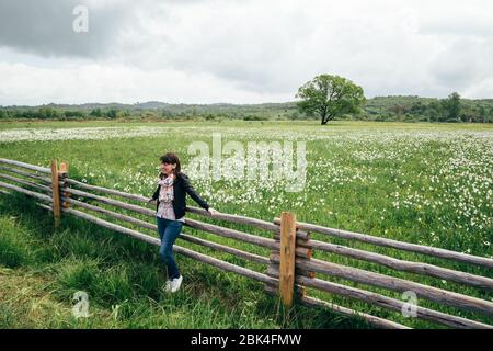 Une jeune femme de tourisme se tenant près de la clôture à la fleur sauvage de la feuille étroite narcissus champ dans l'habitat naturel des basses terres. Célèbre vallée de Narcisse Banque D'Images