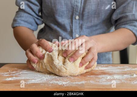 Les mains de Baker font de la pâte sur planche en bois dans la cuisine. Femme pétrir la pâte Banque D'Images