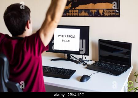 Homme s'étirant tout en travaillant de la maison dans un bureau improvisé dans le salon Banque D'Images