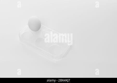 Oeuf de poulet blanc dans un support en plastique isolé sur fond blanc Banque D'Images