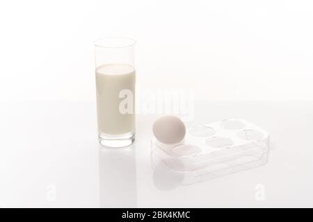 Oeuf de poulet dans un support en plastique et un verre de lait isolé arrière-plan blanc de la cab Banque D'Images