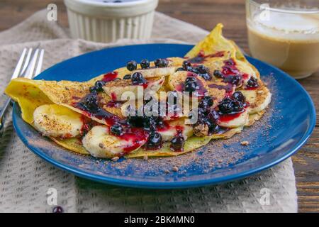 Délicieux crêpes avec bananes, bleuets et miel sur la plaque bleue. Vue rapprochée. Crêpes maison. Crêpes petit déjeuner nourriture Banque D'Images