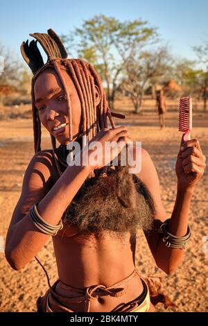 Batwa fille dans la robe traditionnelle combater ses cheveux au coucher du soleil. Banque D'Images