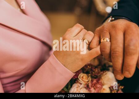 Les nouveaux-mariés se tenant les uns les autres avec peu de doigts et montrant leurs anneaux de mariage. Jour de mariage. Banque D'Images