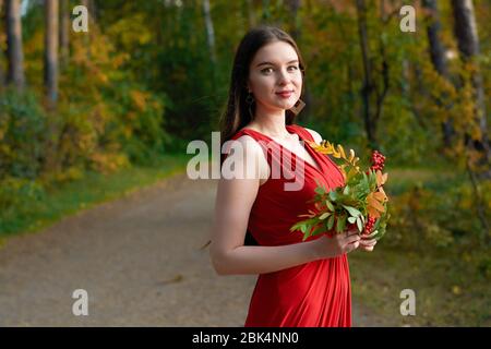 Fille en robe rouge avec un bouquet de cendres dans les bois Banque D'Images