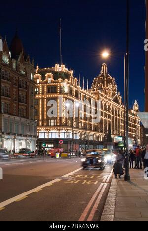 Nuit lumières foncées élévation éclairée avant Knightsbridge Harrods, 87–135 Brompton Road, Londres, Angleterre W3 par Charles William Stephens Banque D'Images