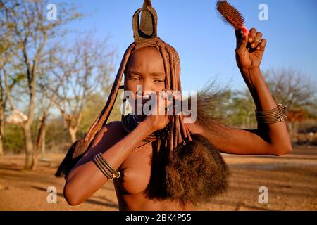 Batwa fille dans la robe traditionnelle combater ses cheveux au coucher du soleil. Banque D'Images