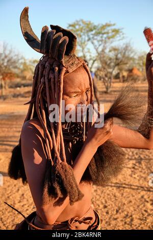 Batwa fille dans la robe traditionnelle combater ses cheveux au coucher du soleil. Banque D'Images