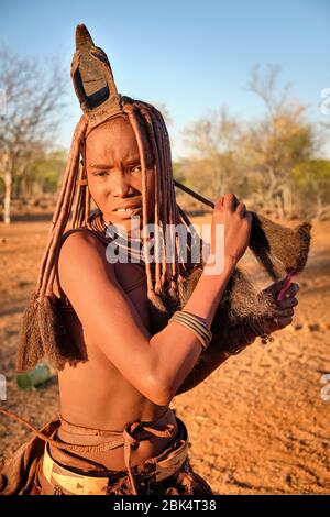 Batwa fille dans la robe traditionnelle combater ses cheveux au coucher du soleil. Banque D'Images