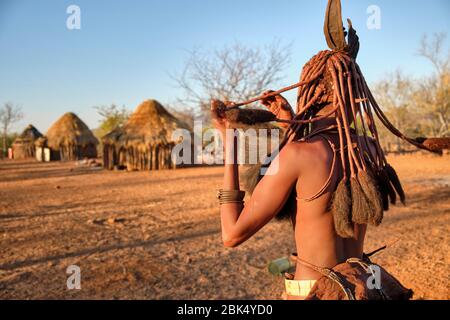 Batwa fille dans la robe traditionnelle combater ses cheveux au coucher du soleil. Banque D'Images