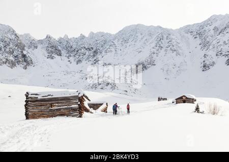 Des amis lors d'une excursion de ski de fond se tiennent à l'extérieur des cabanes en rondins ruinées de la mine de Boston à Mayflower Gulch, Tenmile Range, Colorado. Banque D'Images