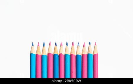Crayons de couleur rose et bleu dans une rangée isolée sur un fond blanc Banque D'Images