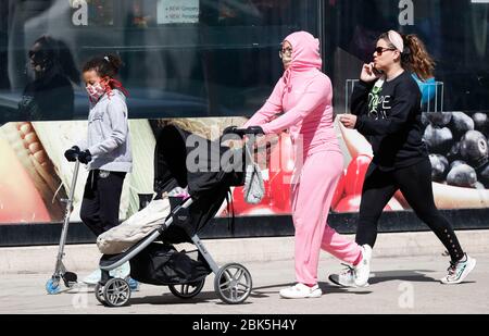 Chicago, États-Unis. 1 mai 2020. Les personnes portant des masques de visage marchent dans une rue à Chicago, Illinois, États-Unis, le 1er mai 2020. L'ordre modifié de séjour à domicile en Illinois, à compter du 1er mai, a rendu obligatoire la couverture faciale dans un lieu public où ils ne peuvent pas maintenir une distance sociale de 6 pieds pour quiconque de plus de deux ans. Crédit: Joel Lerner/Xinhua/Alay Live News Banque D'Images