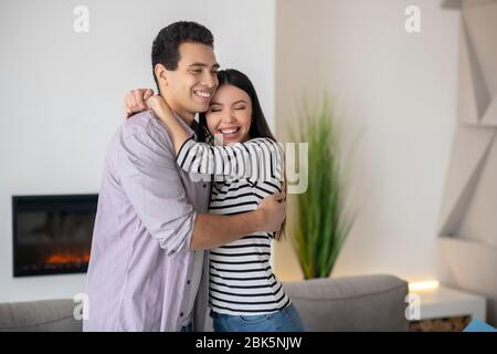 Un jeune homme et une femme heureux embrassant à la maison. Banque D'Images