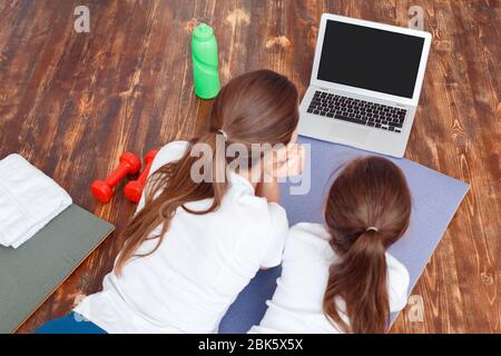 Jeune mère adulte avec sa fille regardant la formation en ligne ensemble à la maison Banque D'Images