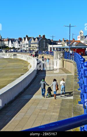 Les gens se baladent le long de la promenade surplombant la plage de la ville balnéaire de Porthcawl. Le Grand Pavillon de l'époque Art déco est loin derrière le café. Banque D'Images