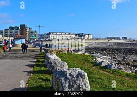 Une vue lointaine sur les bâtiments de bord de mer bordant l'esplanade à Porthcawl.zone de 'plage' artificielle à marée basse.les gens appréciant la marche au bord de la mer. Banque D'Images