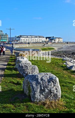 Une vue lointaine sur les bâtiments de bord de mer bordant l'esplanade à Porthcawl.zone de 'plage' artificielle à marée basse.les gens appréciant la marche au bord de la mer. Banque D'Images