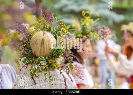 Femmes non identifiées dans des robes traditionnelles avec des couronnes de solstice d'été faites à partir de fleurs de champ, de graminées et de céréales. Banque D'Images