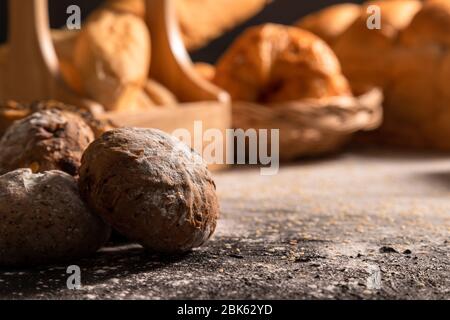 Des pains à la lumière du soleil se ferment le matin sur la table noire en bois avec sésame et variété de boulangerie. Banque D'Images