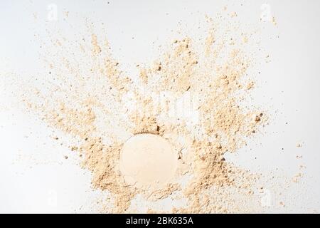 Blanchiment de poudre minérale en vrac.poudre faciale colorée brun clair sur fond blanc. Banque D'Images