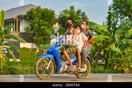 Une famille thaïlandaise voyageant sur une moto, tous portant des masques protecteurs, prise à Pathumthani, Thaïlande, en avril 2020. Banque D'Images