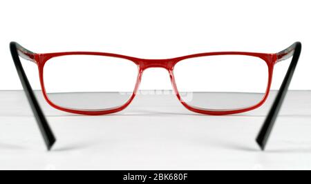 Vue de la première personne d'une paire de lunettes rouges posée sur une table sur un fond blanc Banque D'Images