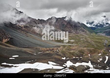 Deux petits grimpeurs au glacier à la vallée de montagne couvert de nuages pluvieux dans Altyn Arashan gorge, Kirghizistan Banque D'Images