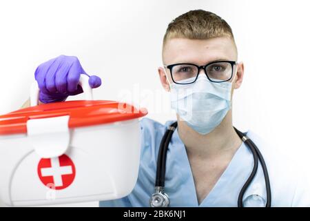 paramedic dans le masque de protection, lunettes et gants en latex bleu contient un boîtier médical Banque D'Images