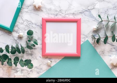 Cadre de Noël en rose saumon et vert menthe. Brindilles d'eucalyptus frais et brindilles de Noël en verre blanc et blanc. Plat, vue sur le dessus sur le dos en marbre blanc Banque D'Images