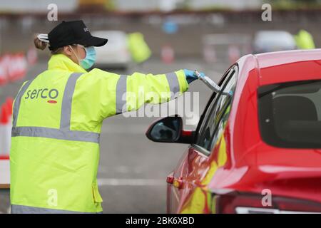 Un membre du personnel remet un kit d'auto-test de Covid-19 de laboratoires de Randox à un membre du public dans un centre de test de conduite à l'SSE Arena de Belfast. Banque D'Images