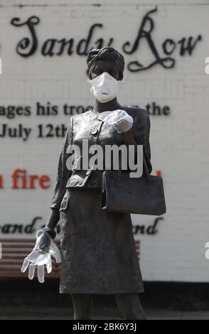 Une statue de l'artiste Ross Wilson, la fille mère sœur, célébrant l'identité et la culture féminines, à Sandy Row Belfast est ornée d'un masque et de gants jetables, tandis que le Royaume-Uni se dirige vers une septième semaine en position de verrouillage pour essayer de limiter la propagation du coronavirus. Banque D'Images