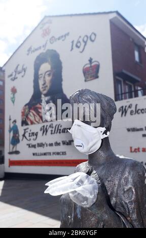 Une statue de l'artiste Ross Wilson, la fille mère sœur, célébrant l'identité et la culture féminines, à Sandy Row Belfast est ornée d'un masque et de gants jetables, tandis que le Royaume-Uni se dirige vers une septième semaine en position de verrouillage pour essayer de limiter la propagation du coronavirus. Banque D'Images