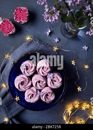 Bleu-violet doux maison Zephyr ou Marshmallow de cassis près des fleurs lilas et des étoiles magiques lumières sur fond sombre vue de dessus Banque D'Images